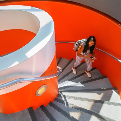 A student climbs the circular staircase into Uris Library from the Cocktail Lounge